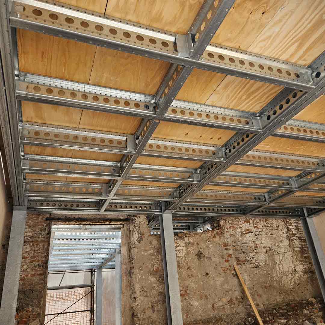 Interno di un ex edificio industriale riqualificato in loft residenziale con ampio soppalco in carpenteria metallica e parapetti in vetro